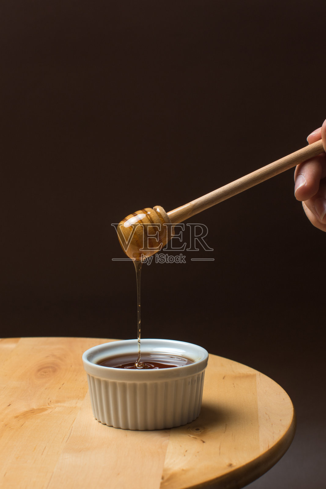 蜂蜜和蜂蜜勺放在木桌上，深色的背景照片摄影图片