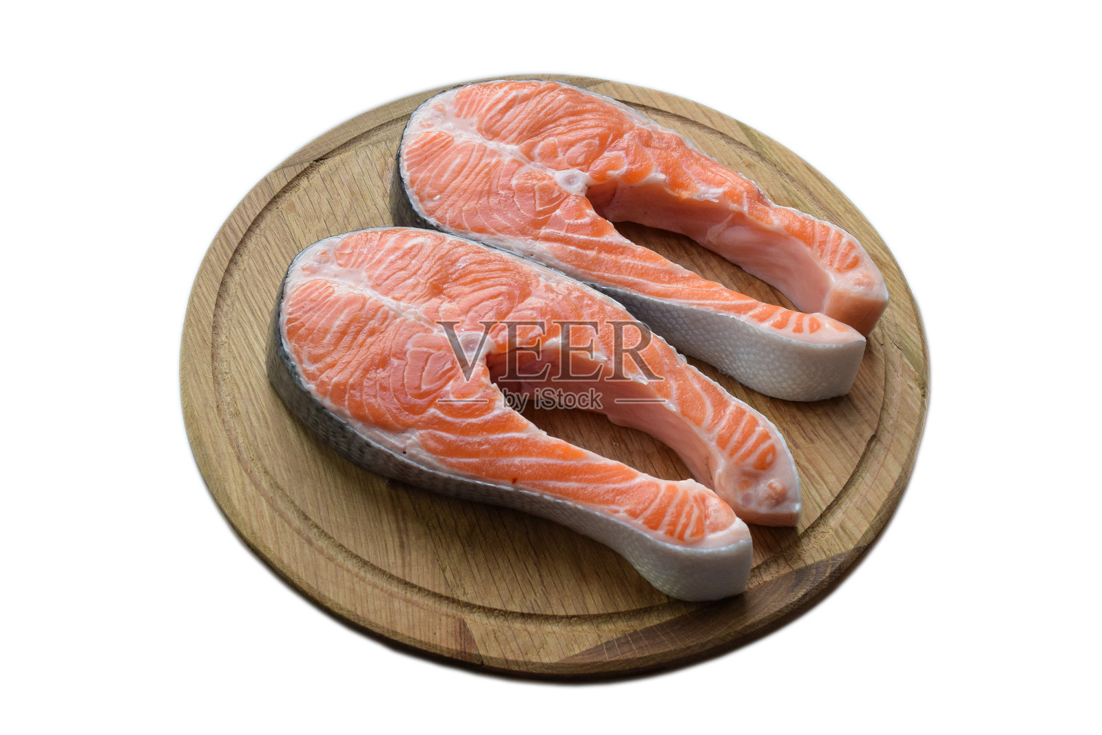 圆形的木砧板上放着两块红色的鱼肉。在白色剪辑背景照片摄影图片