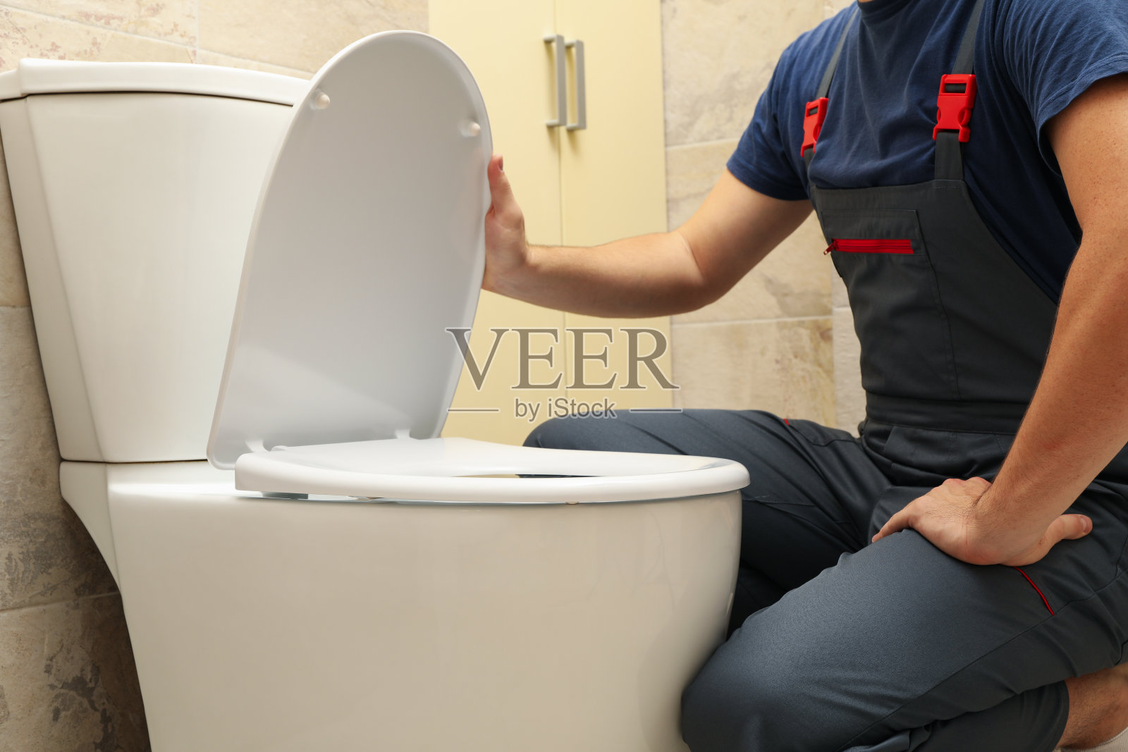 穿工装裤的水管工修理马桶照片摄影图片