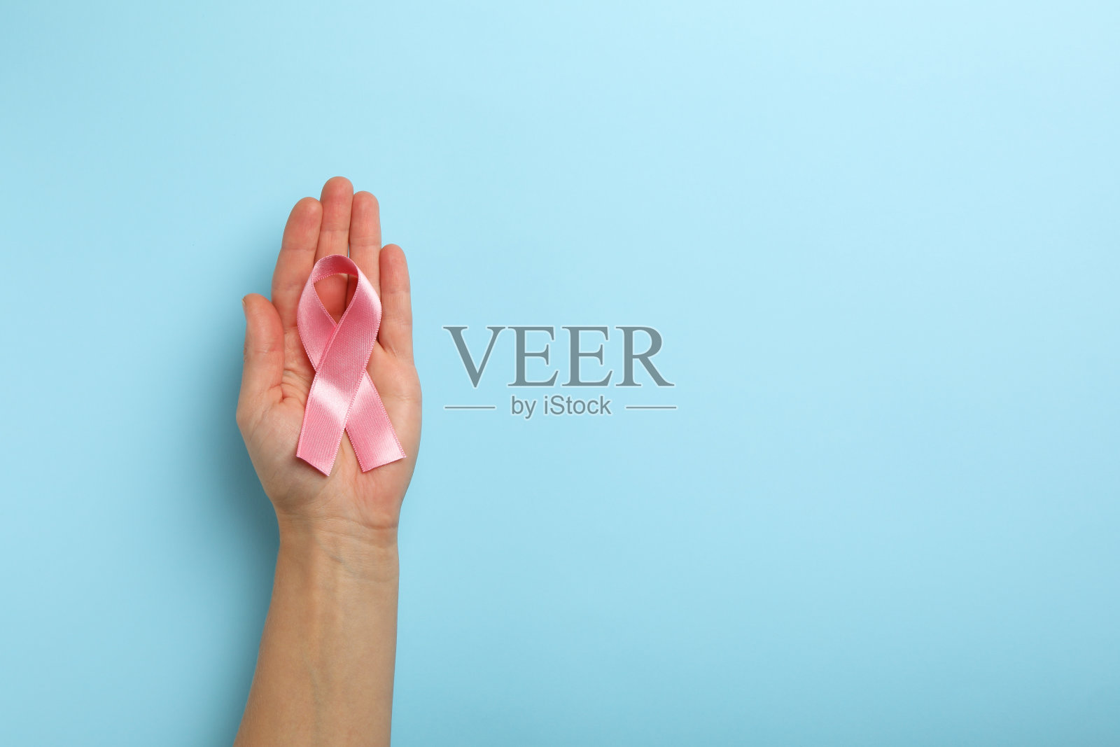 女性手与粉色意识丝带在蓝色背景照片摄影图片