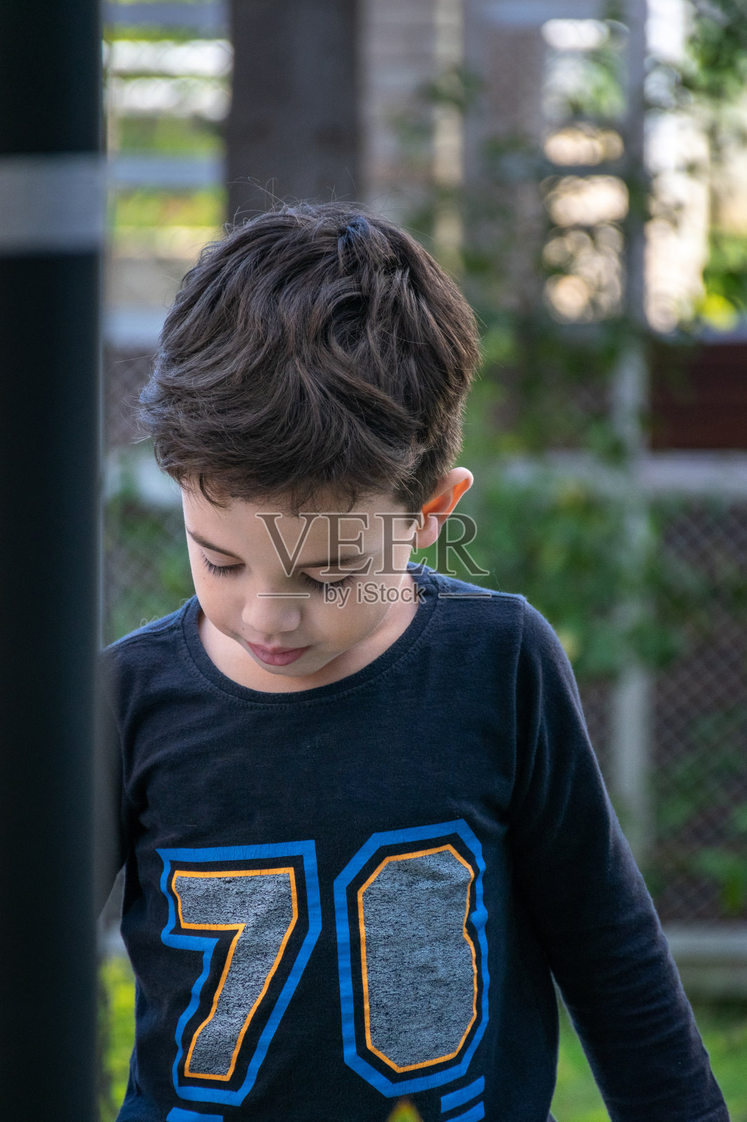 悲伤和沉思的孩子在花园里向下看。照片摄影图片