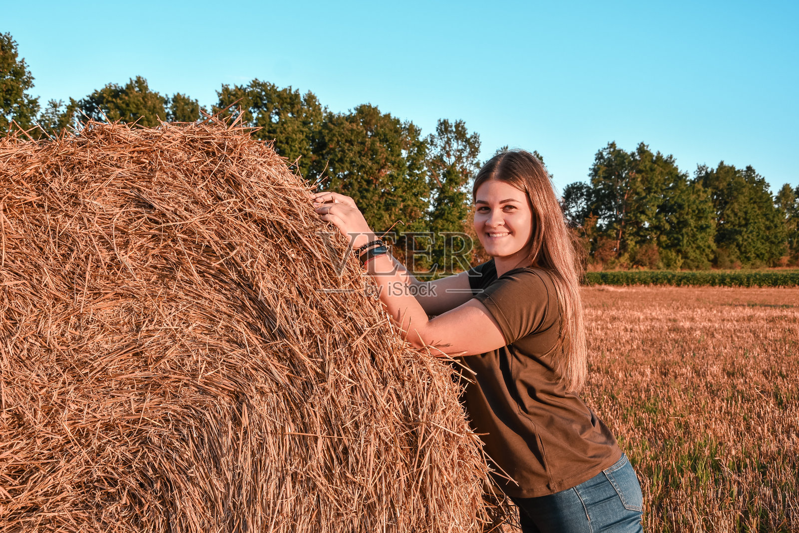 肖像的年轻幸福微笑的女人在干草堆日落，农村。享受发现的乐趣，享受大自然的新鲜空气。Cottagecore照片摄影图片