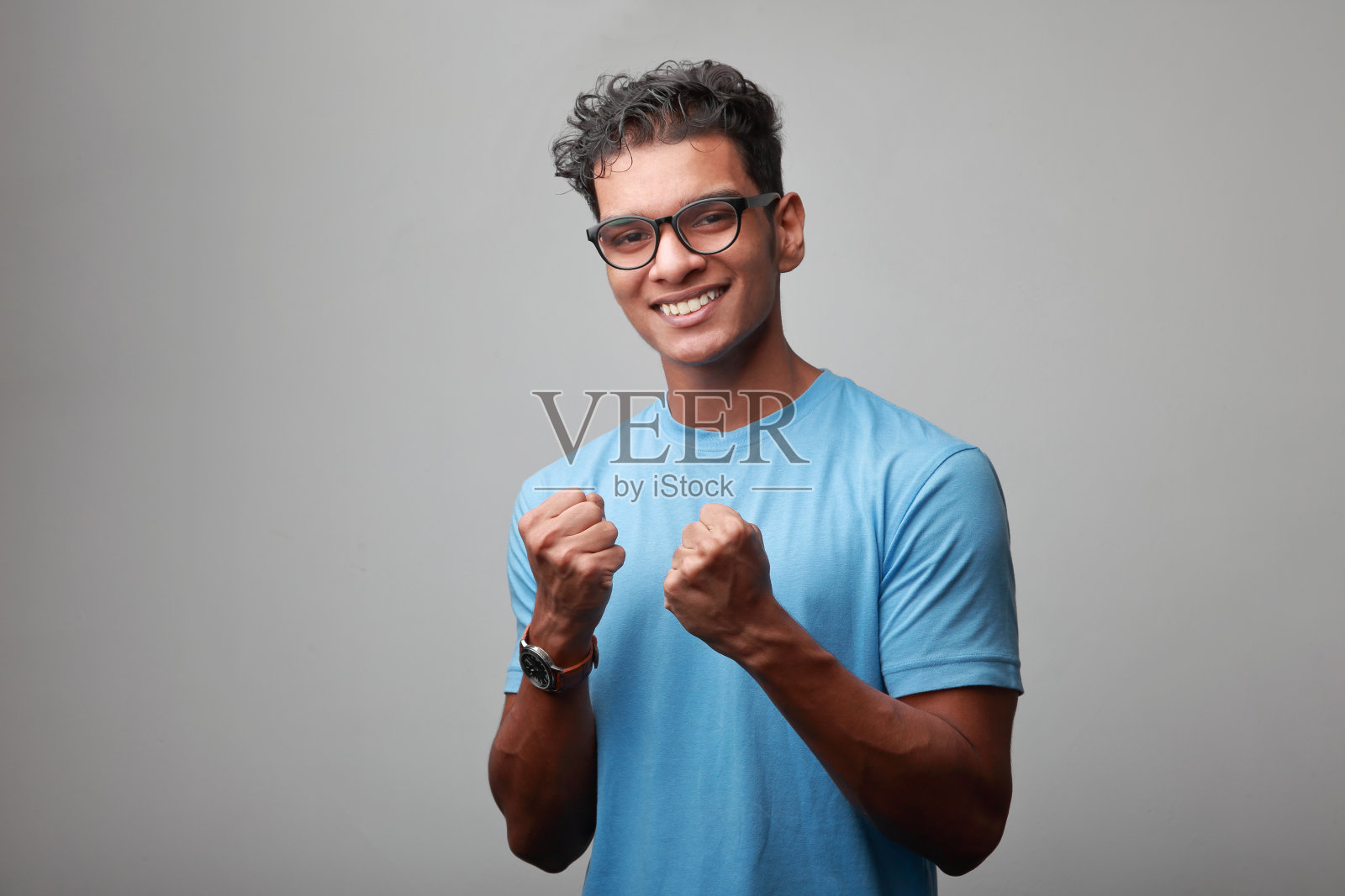 一个快乐的印第安裔年轻人的肖像，他摆着欢呼的姿势照片摄影图片