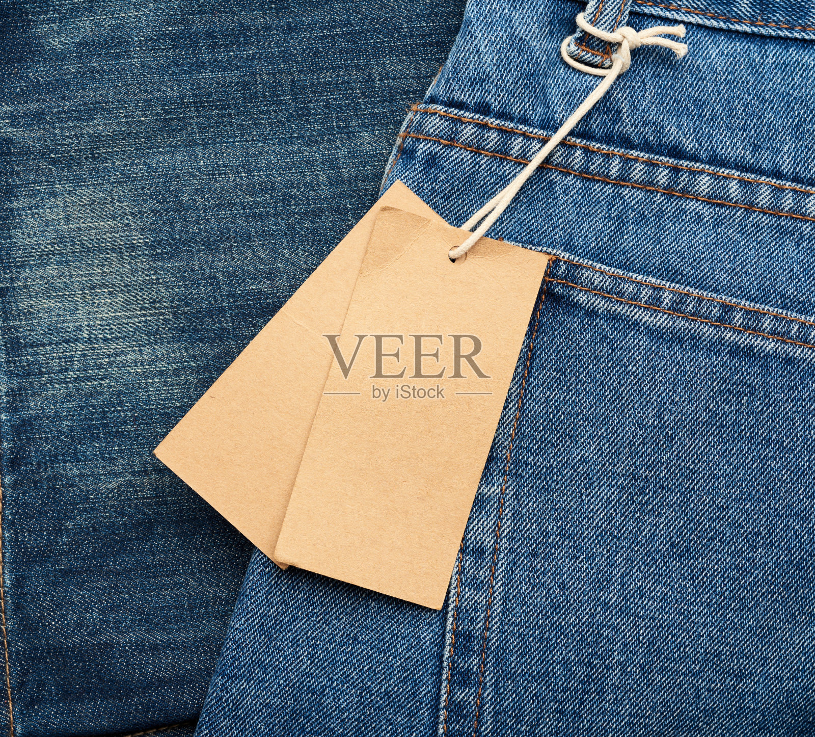 空白棕色矩形标签系在蓝色折叠牛仔裤的后口袋照片摄影图片