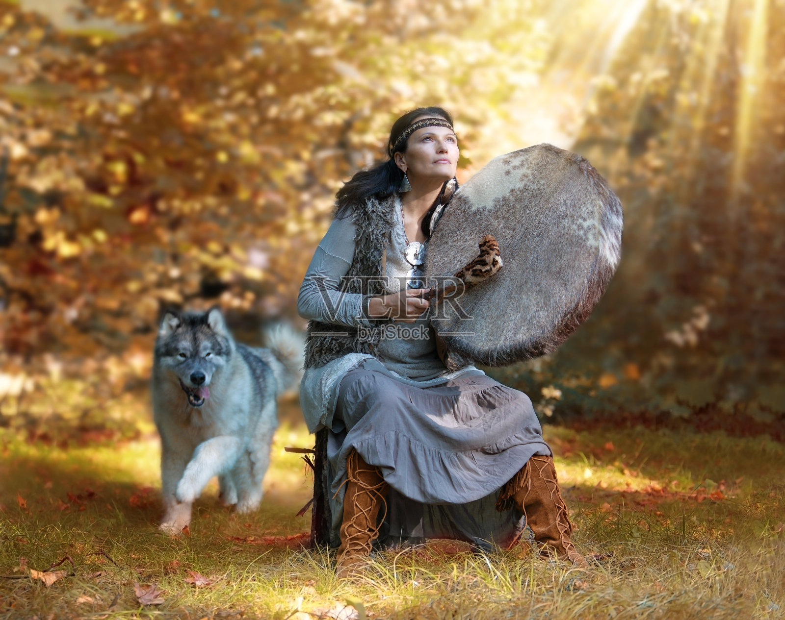 萨满女子在森林里与阿拉斯加雪橇犬打鼓照片摄影图片