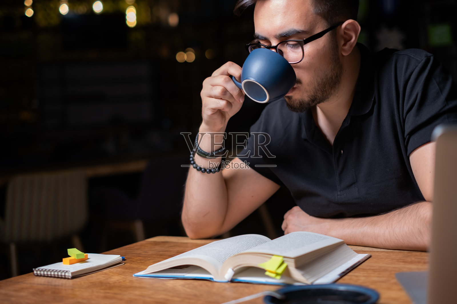 年轻人一边看书一边喝咖啡照片摄影图片