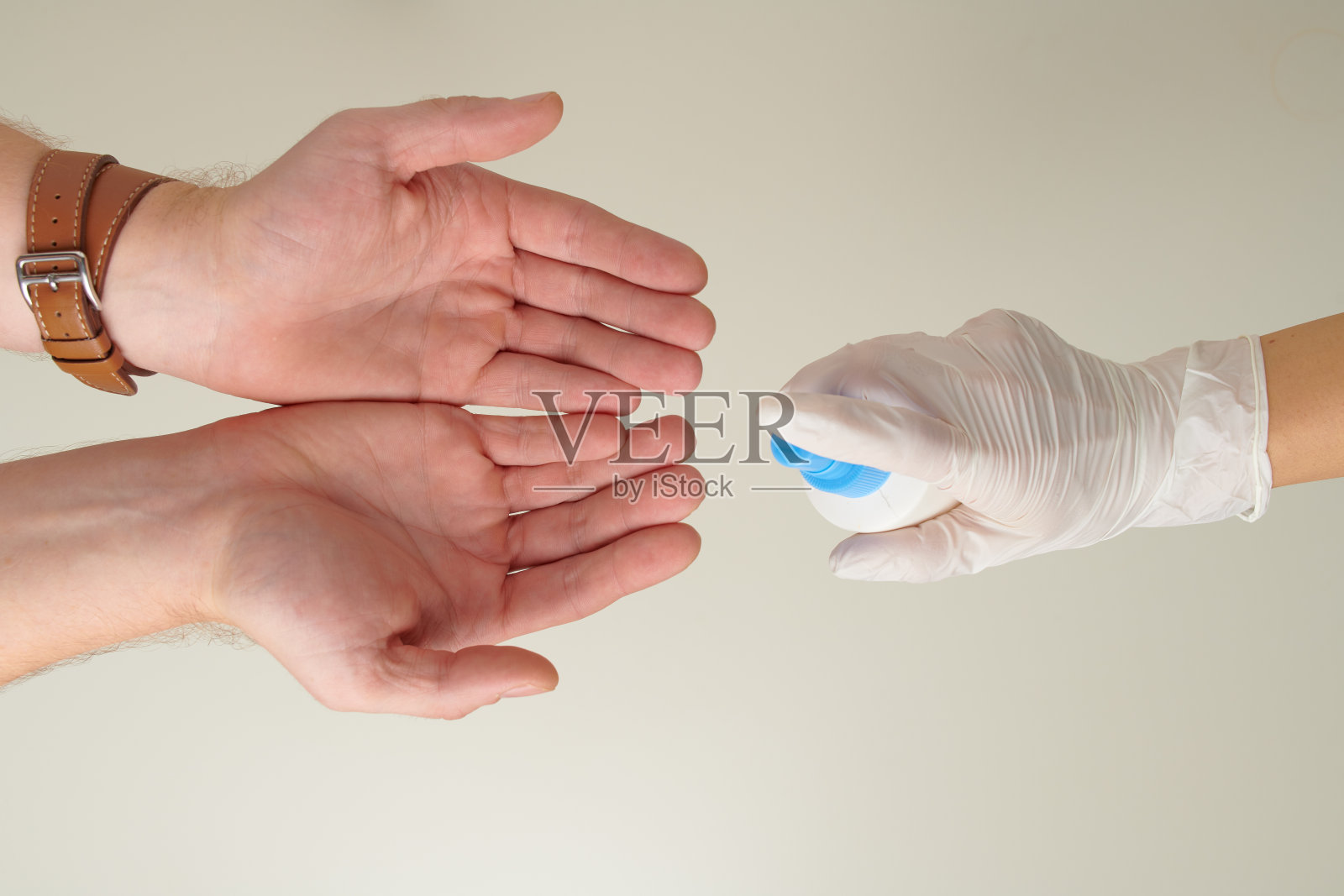 手戴橡胶手套，用消毒液消毒男性双手照片摄影图片