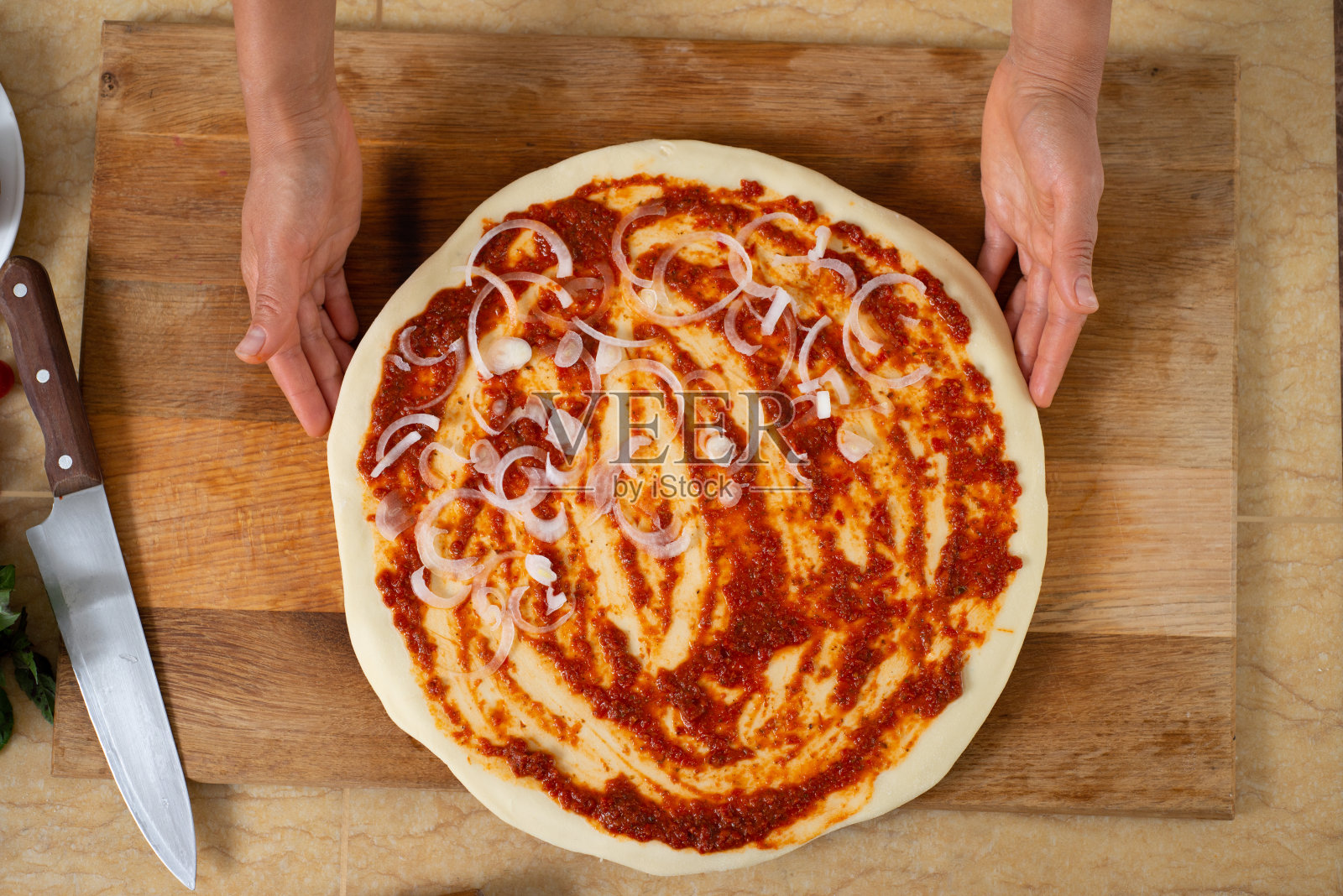 厨师展示一块部分展开的馅料的手的视图。做不含奶酪的素食披萨。照片摄影图片