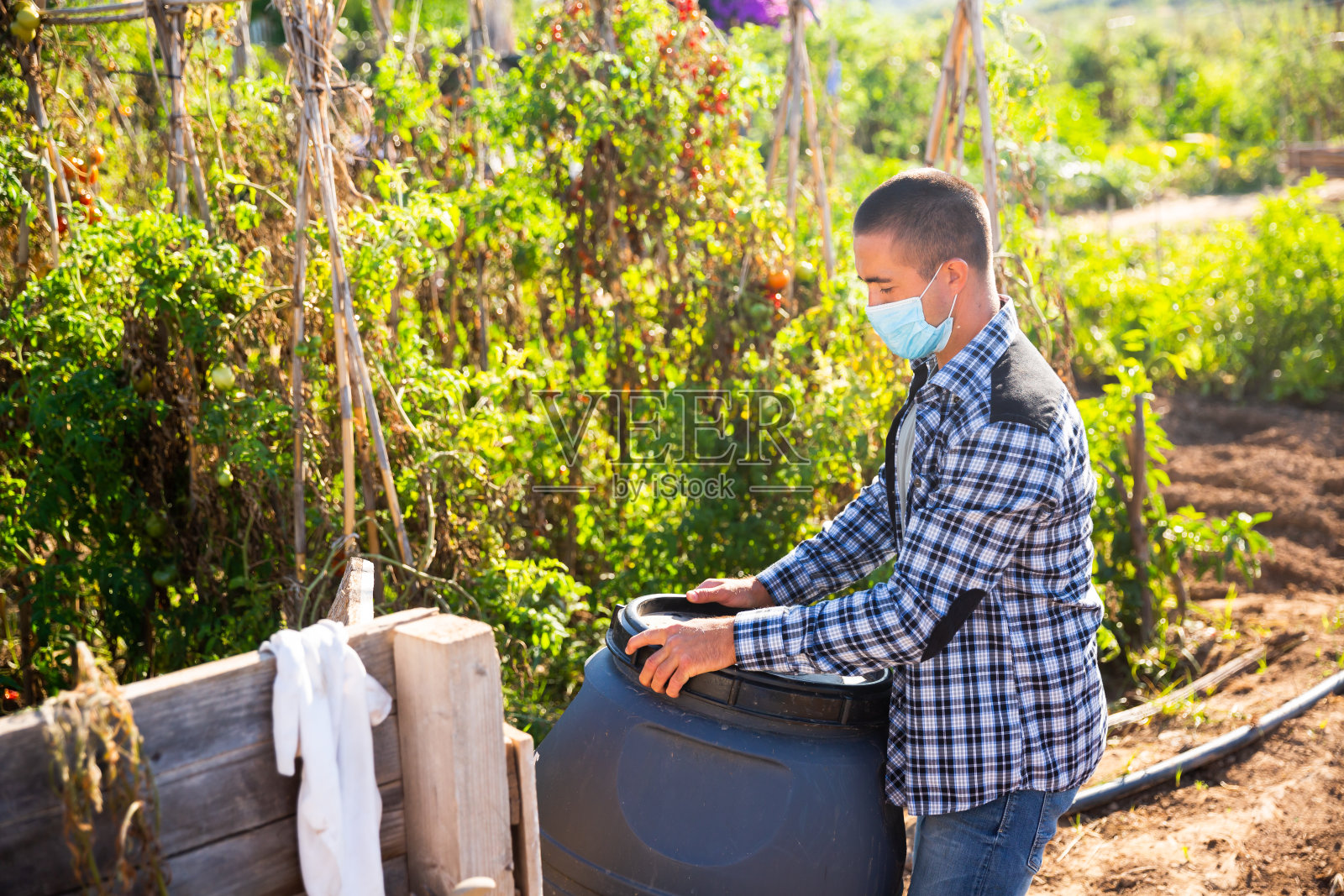 男工人戴着面具整理花园桶照片摄影图片