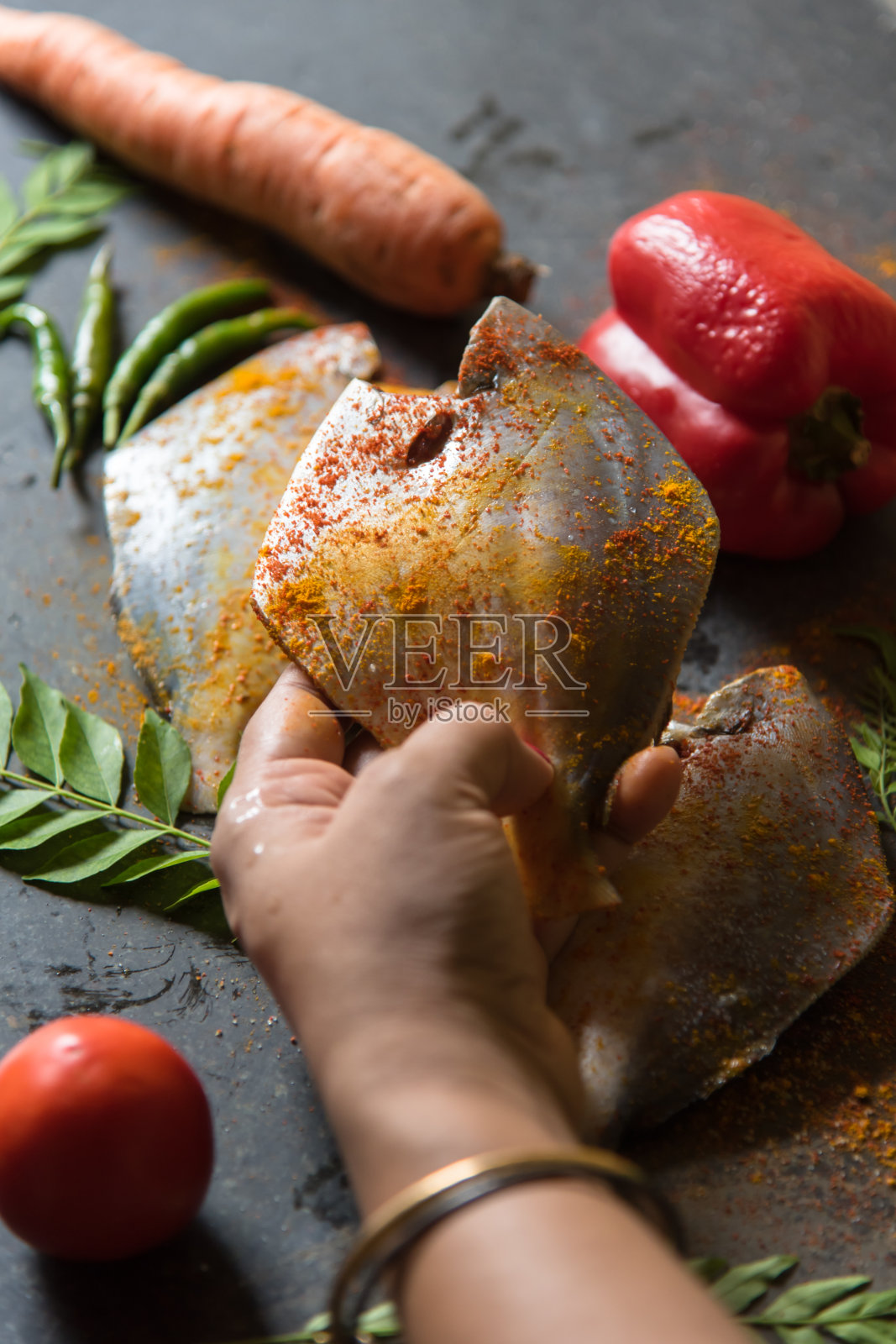 女手拿着一条新鲜腌制的生鲳鱼照片摄影图片