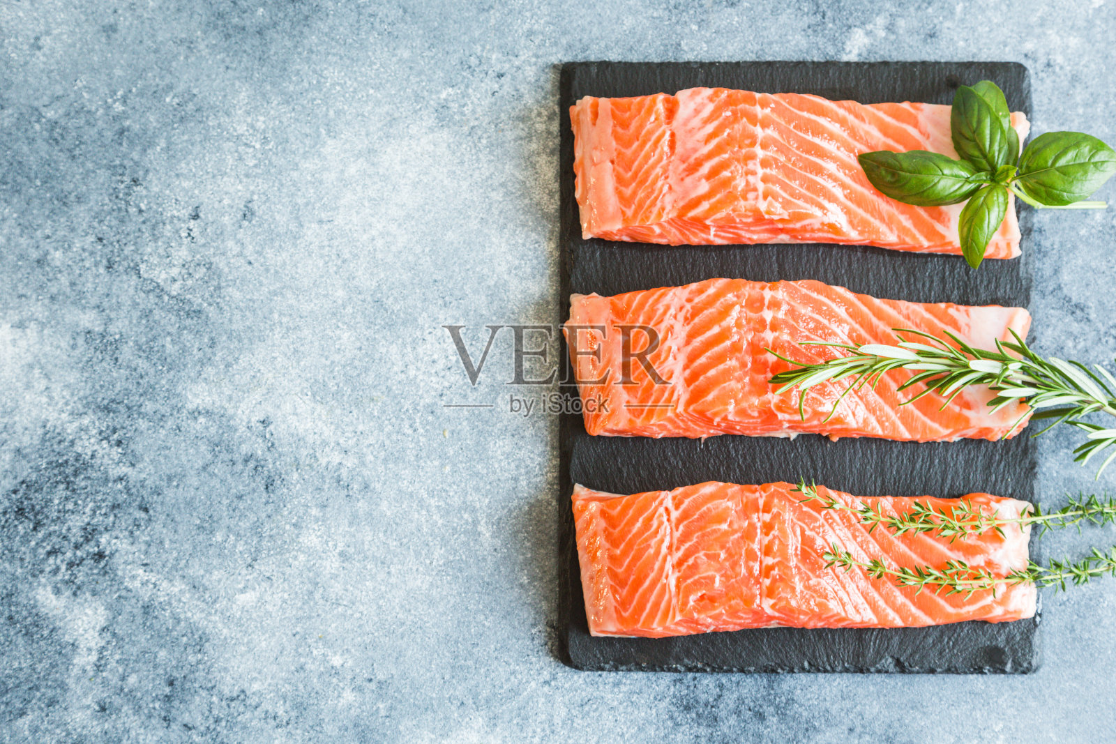 鲑鱼。新鲜的生鲑鱼片，配以烹饪原料，香草和柠檬。关闭了。健康的食物，饮食或烹饪概念照片摄影图片