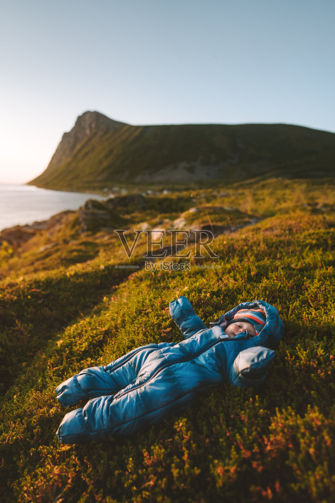 婴儿旅行者躺在苔藓上放松与山和海景家庭活动健康的生活方式与孩子度假户外儿童穿着连衣裤探索自然照片摄影图片