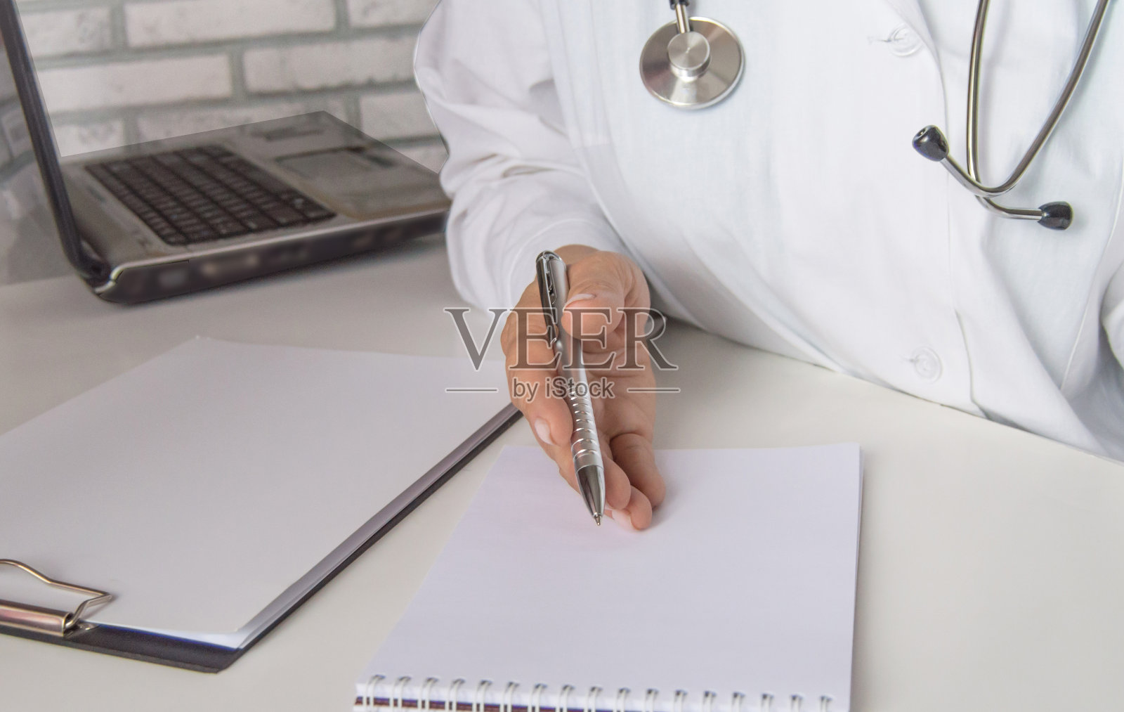 一名女医生在医务室的笔记本电脑前与病人交谈，解释治疗的概念照片摄影图片