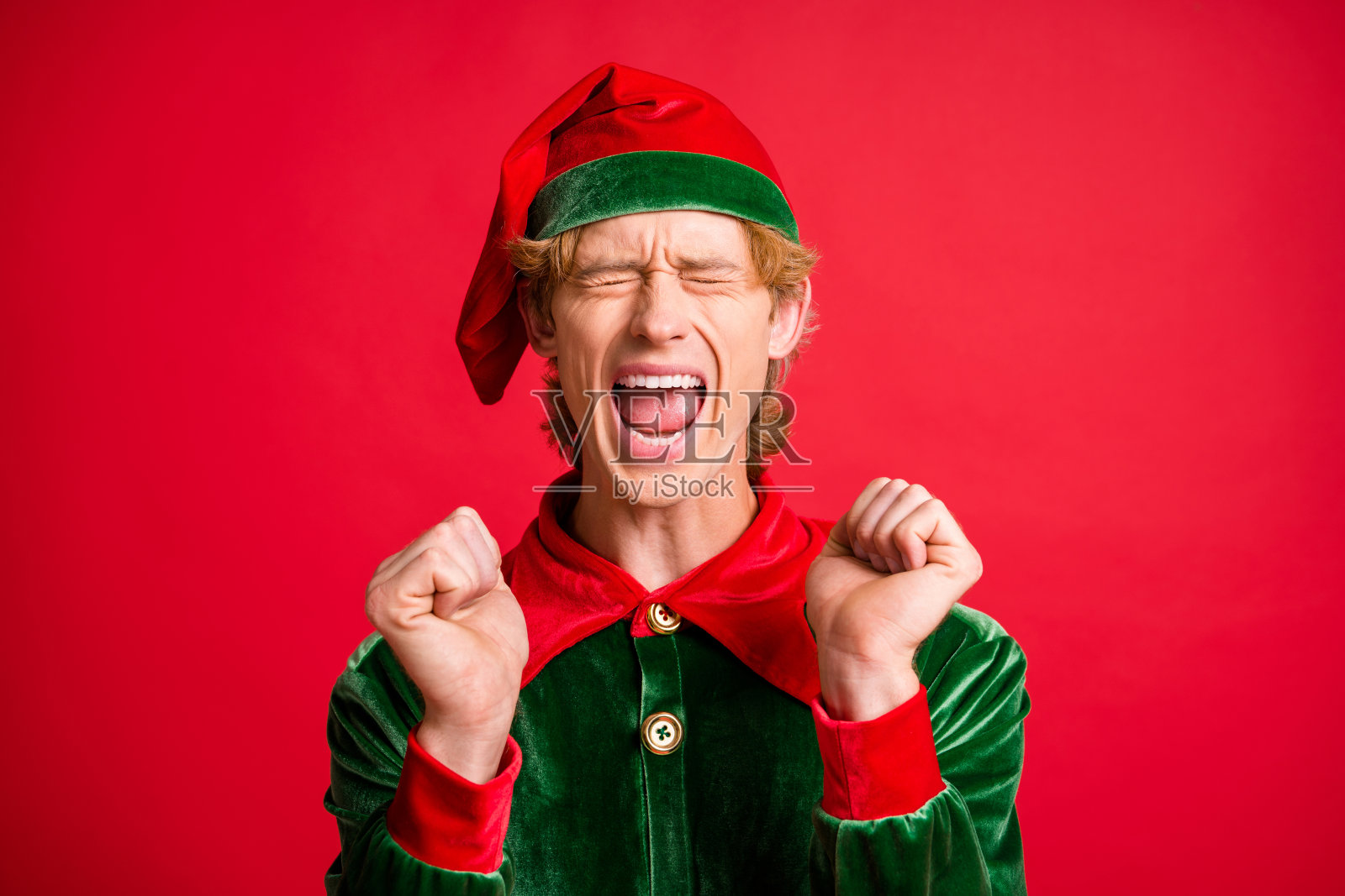 疯狂的欣喜若狂的精灵家伙举起拳头尖叫圣诞圣诞魔术礼物概念孤立在红色发光的颜色背景照片摄影图片