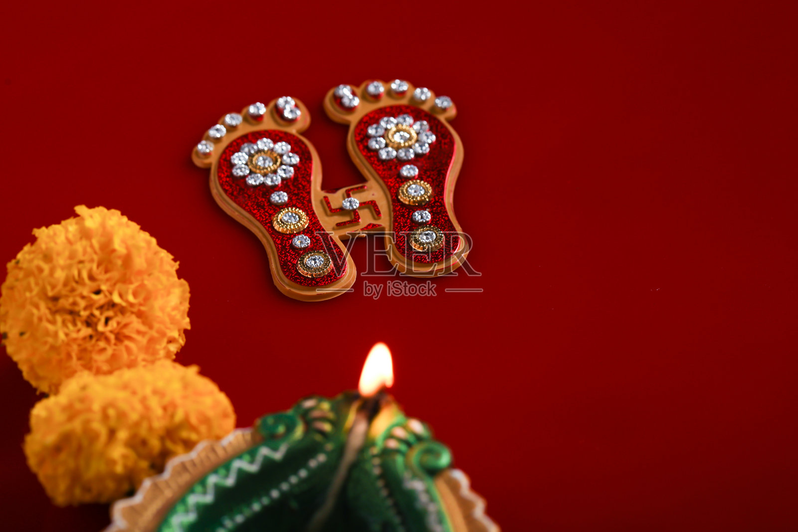 庆祝印度节日:女神拉克希米手工足迹金盏花和油灯在红色的背景照片摄影图片