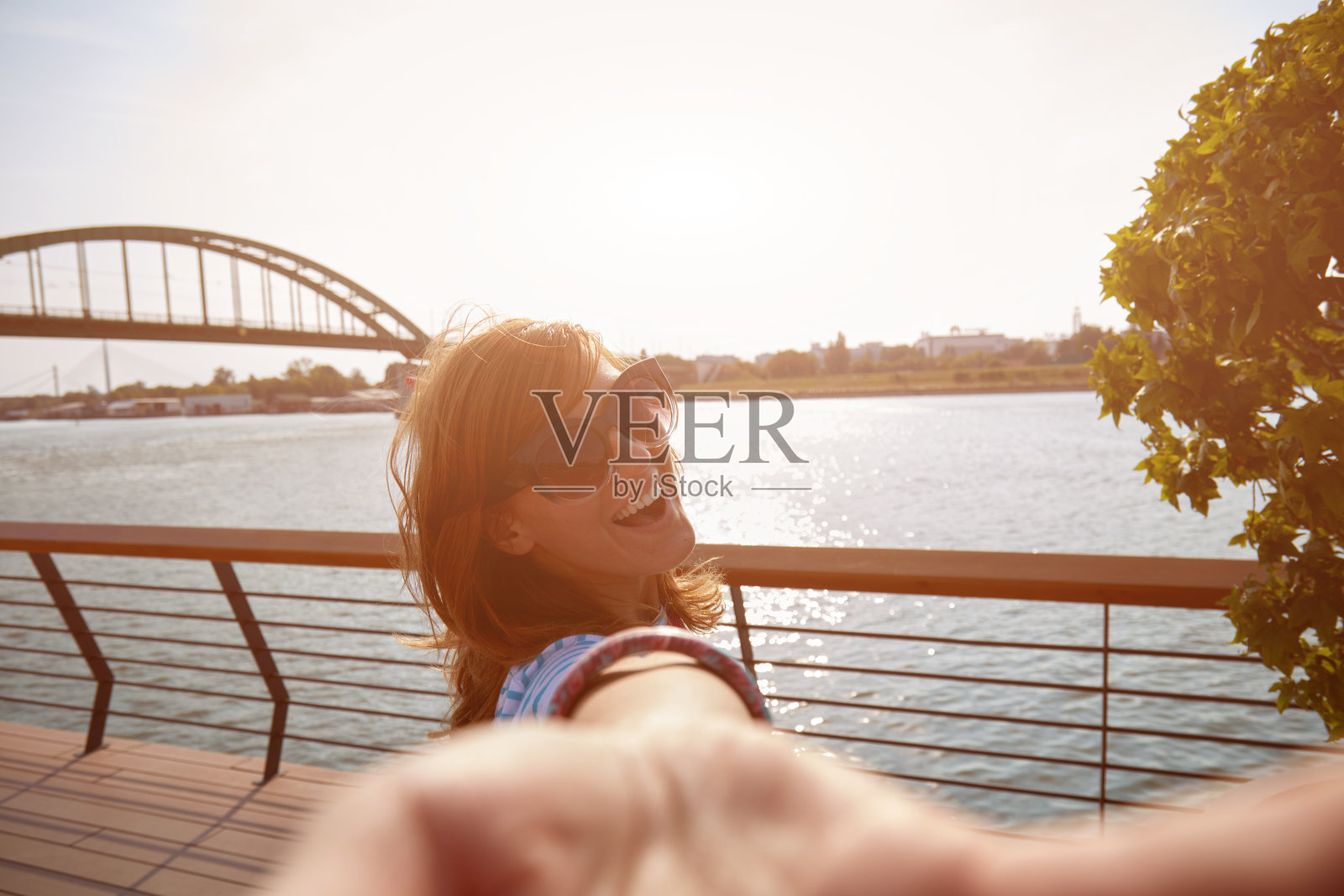 在城市环境中，年轻女子在河边户外自拍。照片摄影图片