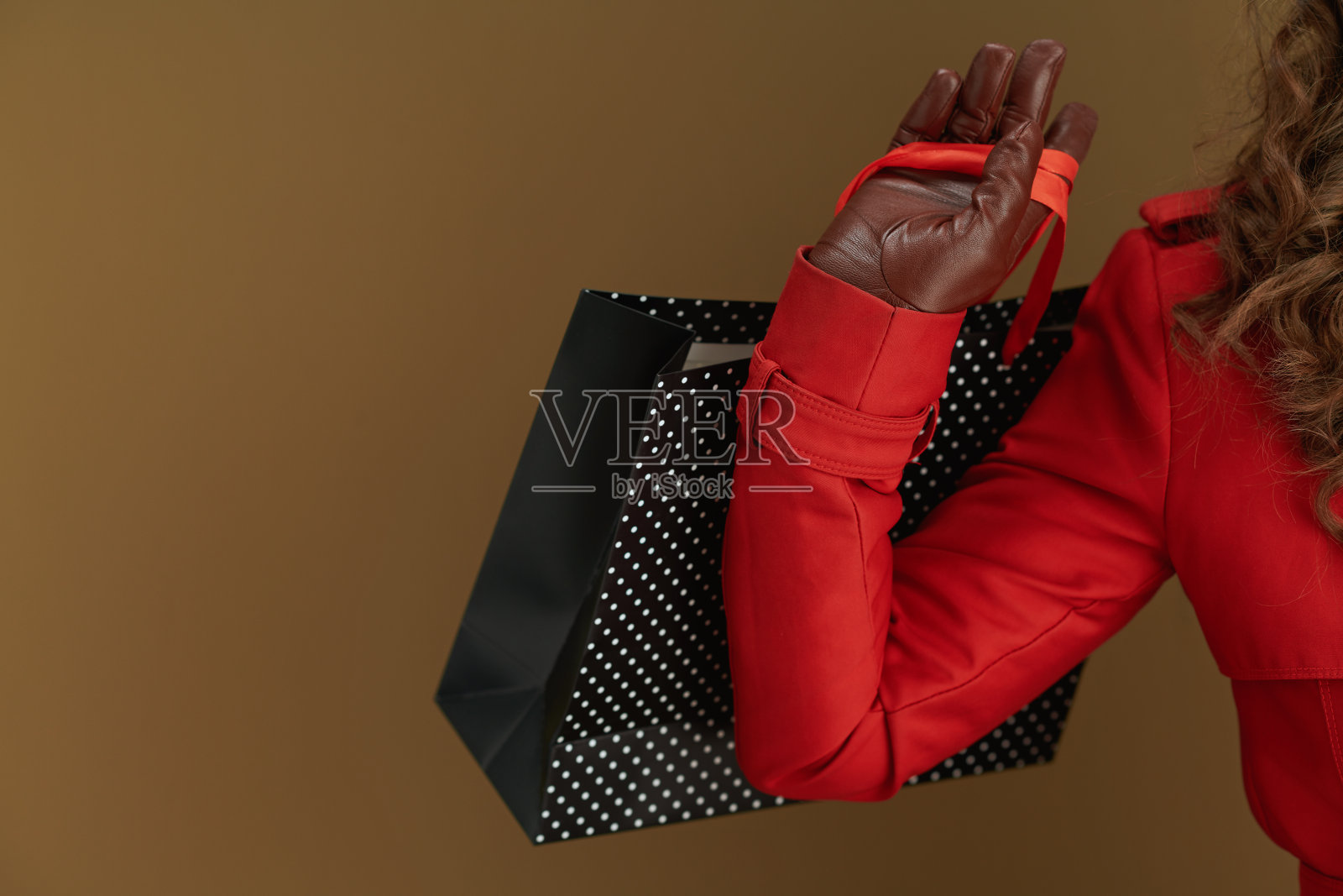 穿着红色外套和贝雷帽的现代女性，孤立在棕色背景下照片摄影图片