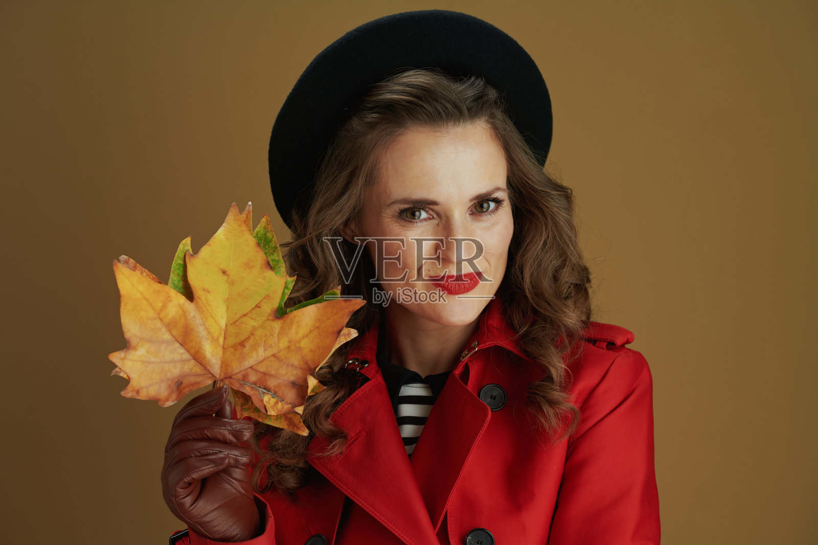 快乐的现代女性在米色背景下的外套和贝雷帽照片摄影图片