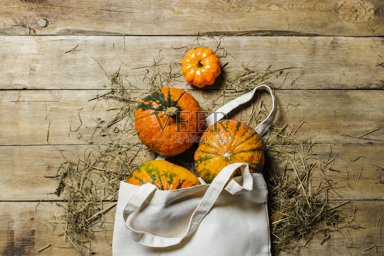 木制背景的购物袋里的南瓜。收获的概念，秋天，万圣节前夕。横幅。平铺，俯视图照片摄影图片
