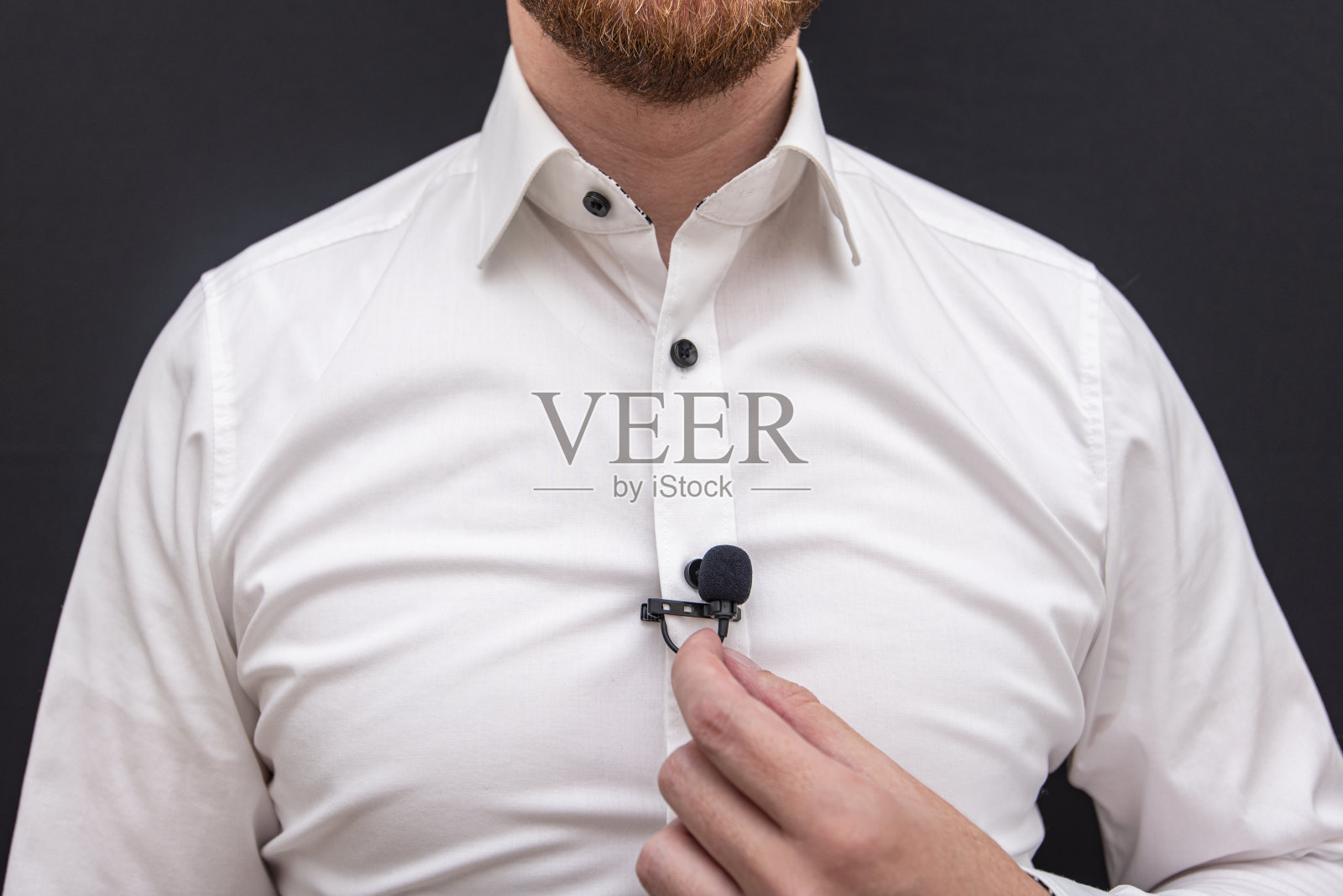 一个穿着白衬衫拿着小麦克风的男人照片摄影图片