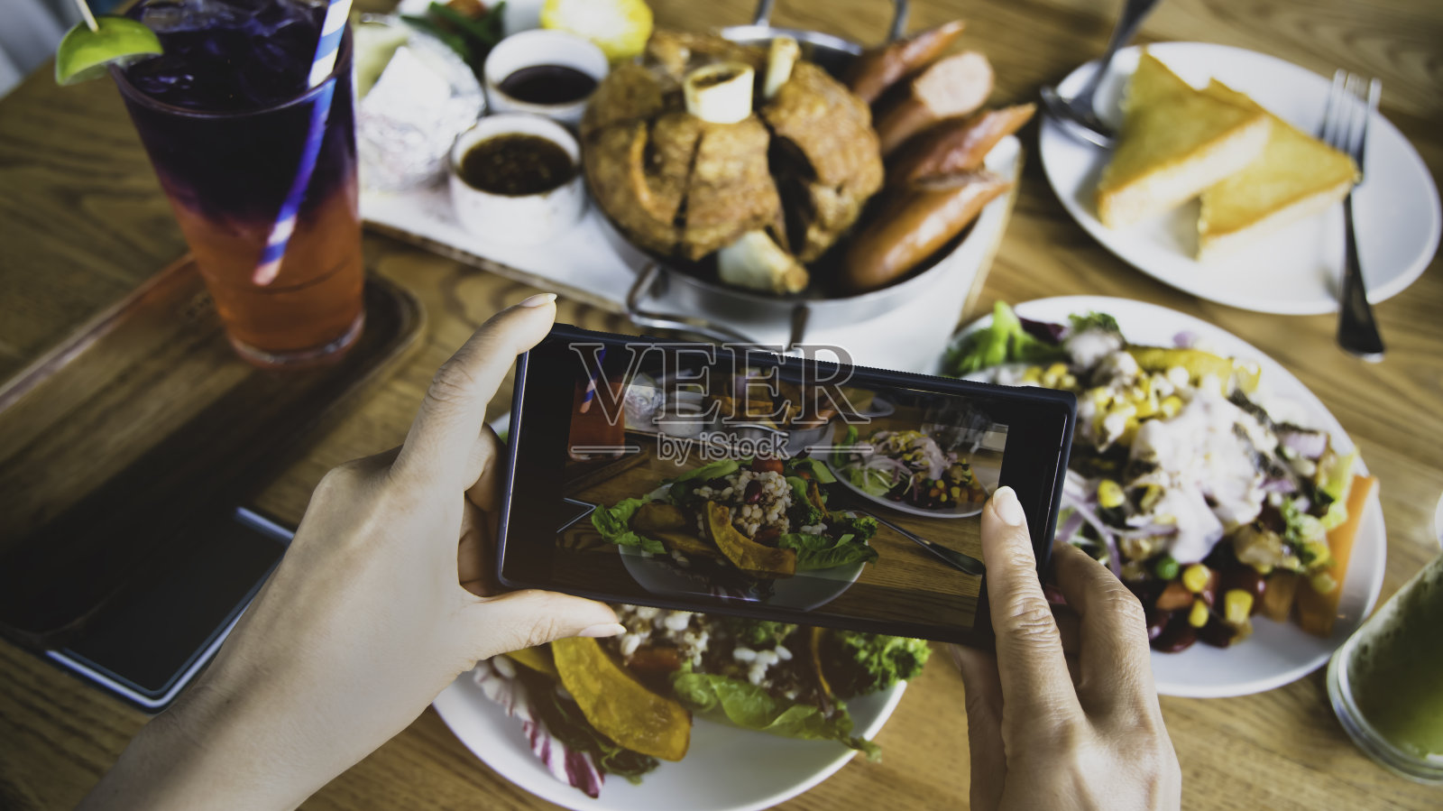 近距离观察一名女性博主在餐厅用餐前用手机拍照的场景——复古的基调照片摄影图片