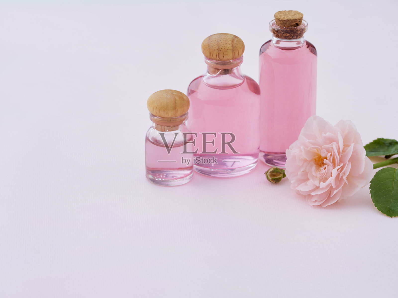 香薰油瓶与玫瑰在粉红色的背景照片摄影图片