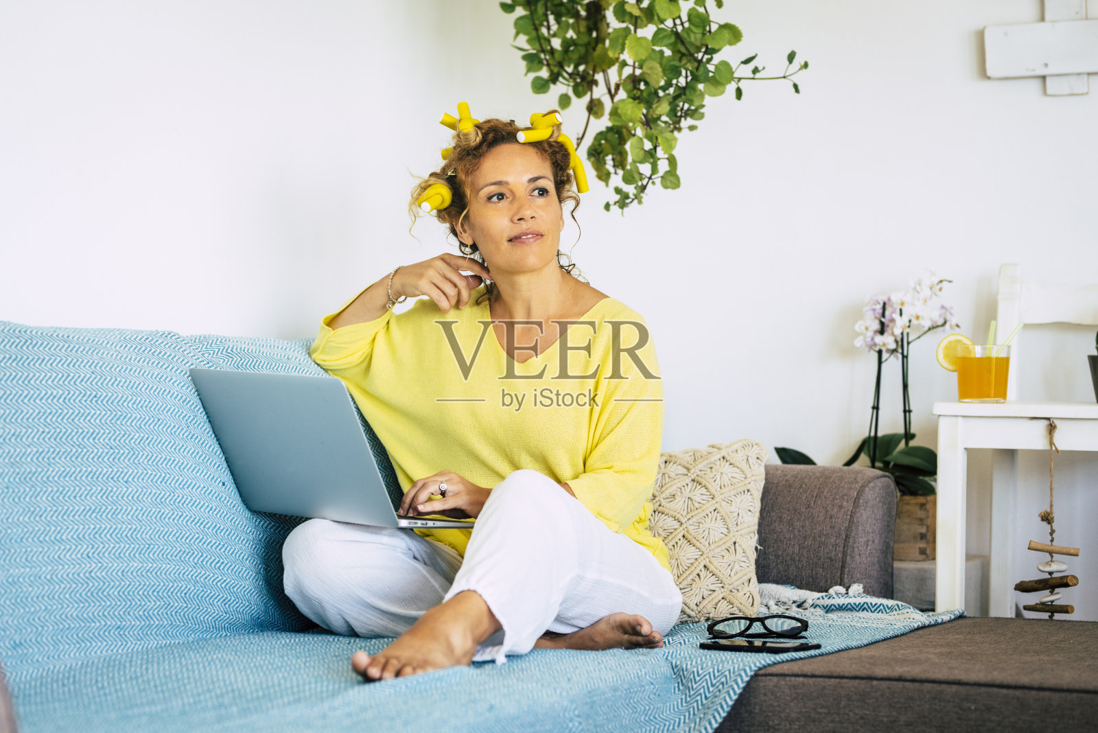 美丽的女人在家里的智能工作活动，坐在沙发上工作的笔记本电脑-现代的人和技术概念的生活方式-新的家庭办公工作站照片摄影图片