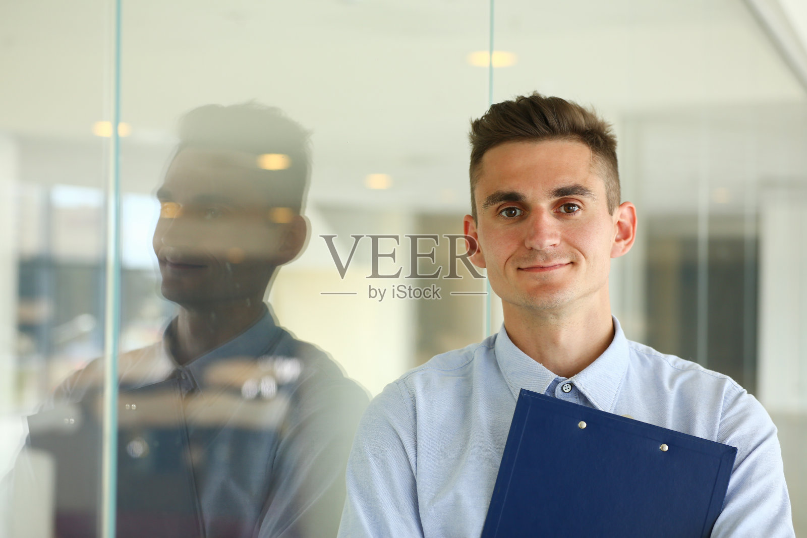 英俊的年轻人站在玻璃墙旁边照片摄影图片