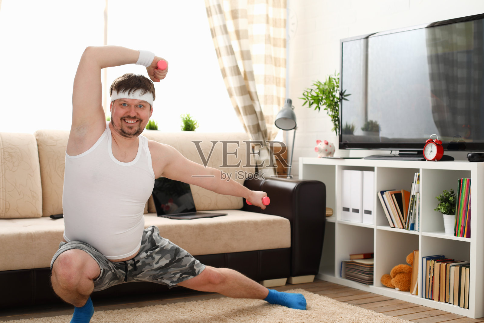 一个愉快的年轻人在家里用哑铃做运动照片摄影图片