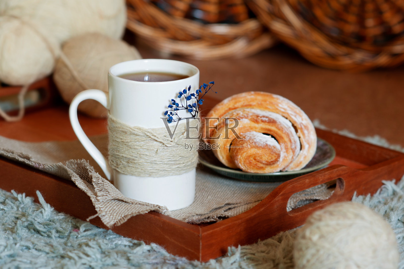 针织茶杯与羊角面包木托盘，舒适地毯和毛线球照片摄影图片