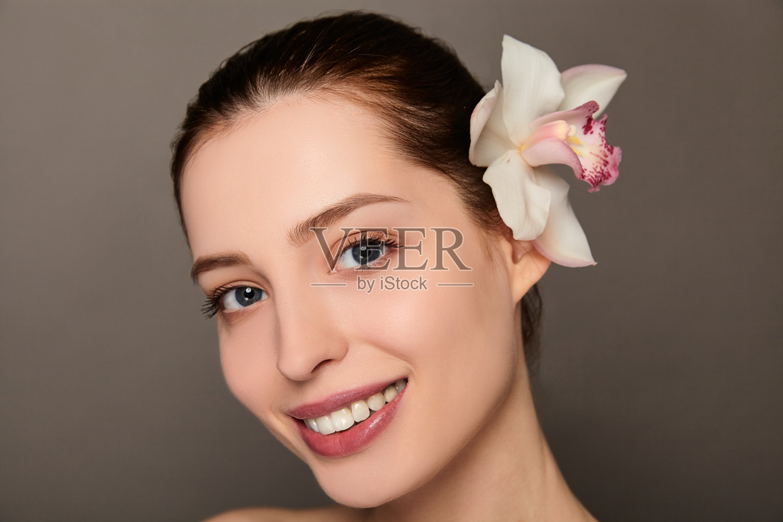 一个年轻美丽的女孩与兰花的特写肖像。照片摄影图片