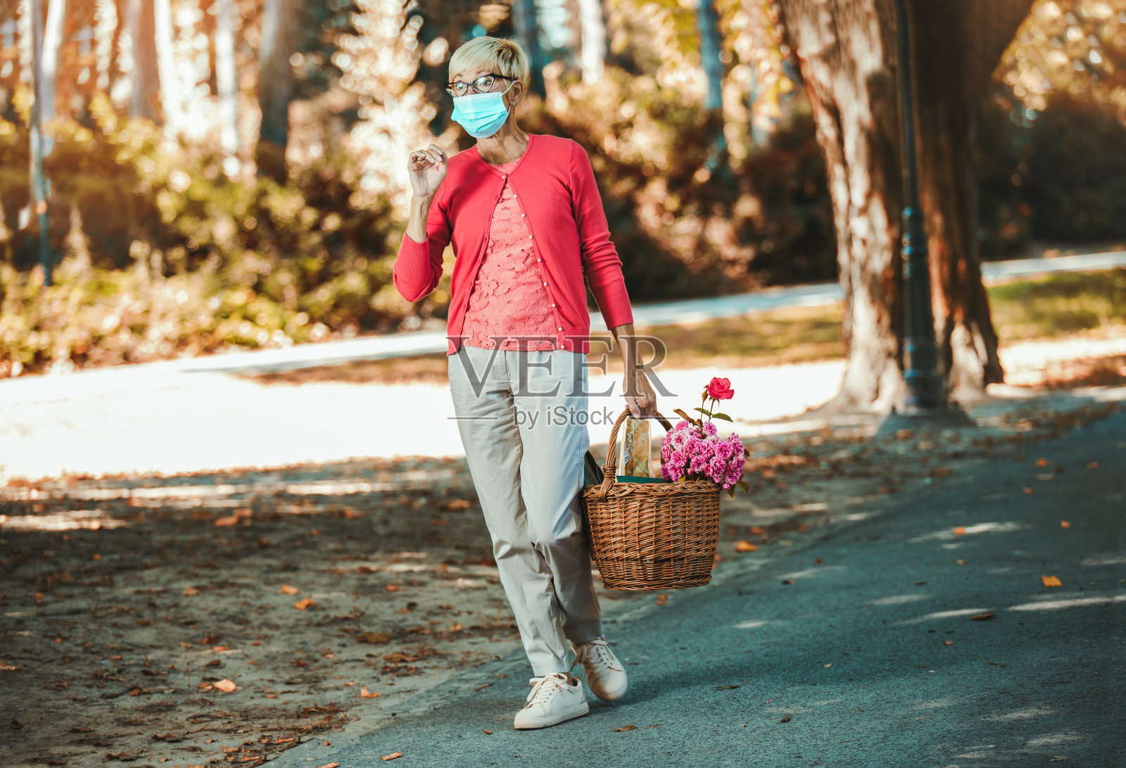 老妇人戴着口罩，提着篮子去市场。照片摄影图片