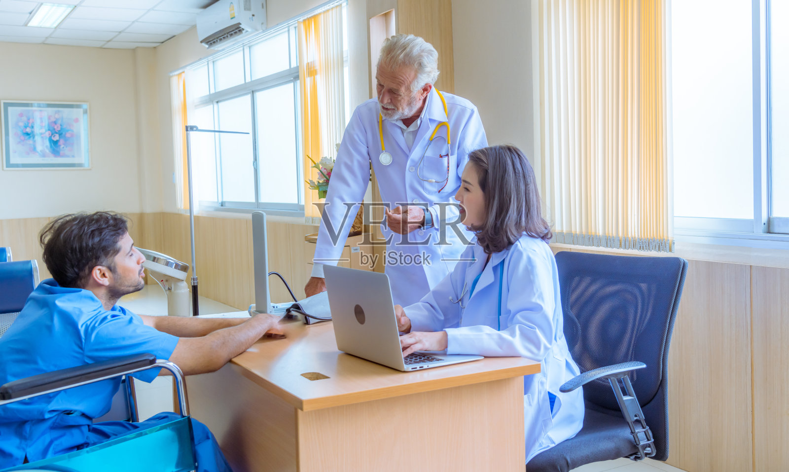 医生和护士在检查和咨询病人，他们戴着医用口罩，以防止病毒在医院照片摄影图片