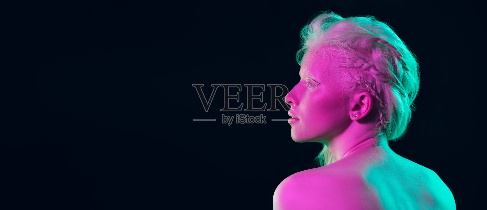 美丽的白化病女孩的肖像孤立在黑暗的工作室背景霓虹灯照片摄影图片