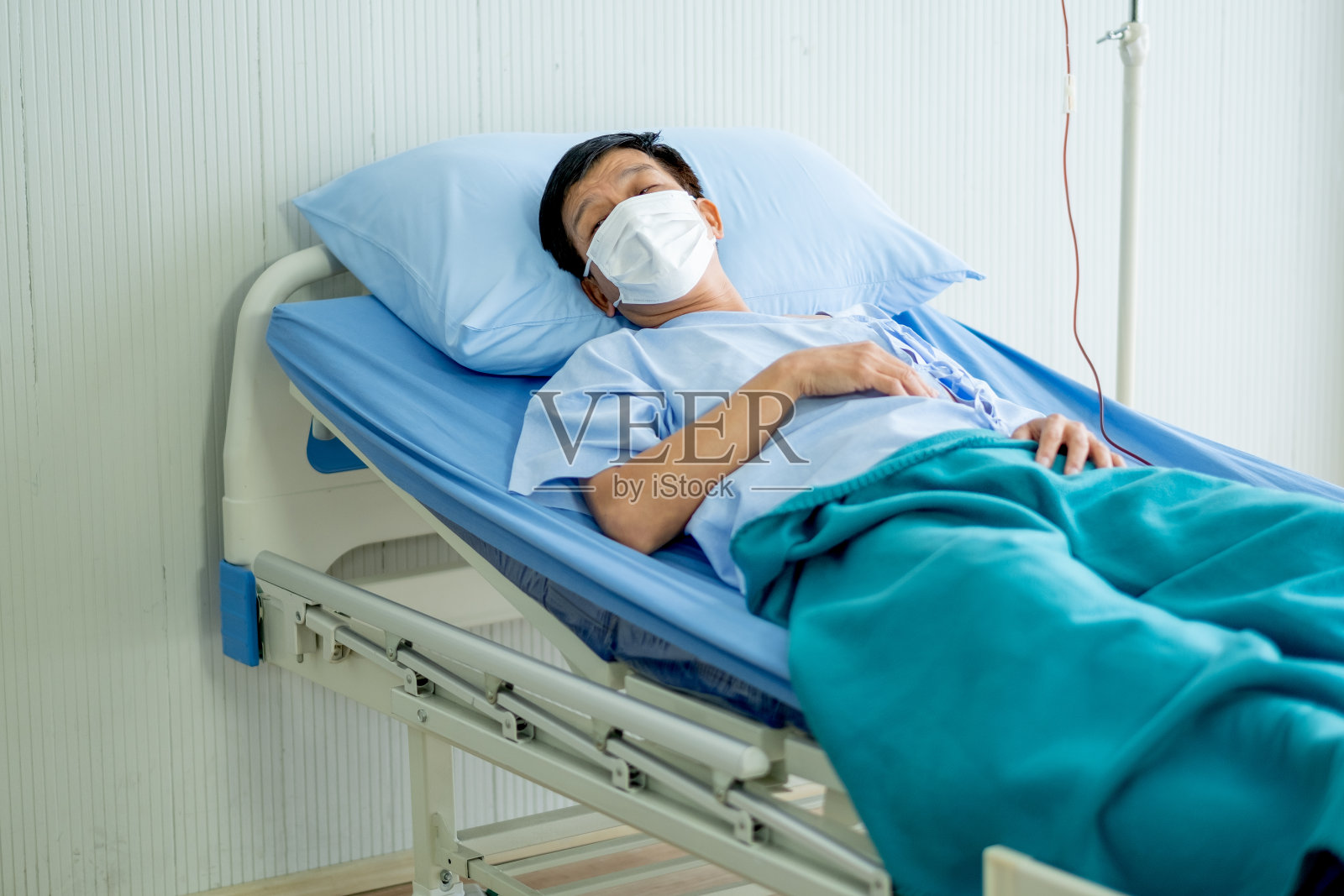 2019冠状病毒感染者戴口罩躺在医院封闭病房的床上，看起来疲惫、悲伤，需要别人的鼓励照片摄影图片