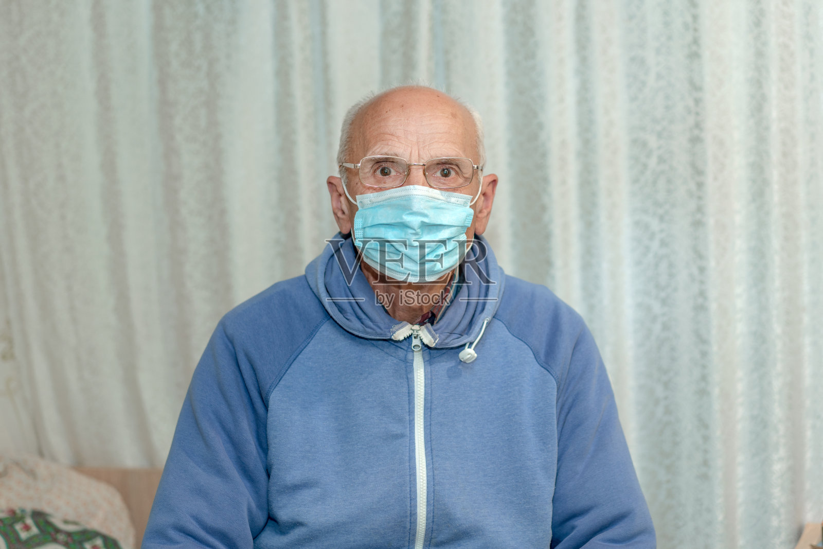 戴医用防护口罩坐在医院或疗养院病床上的生病老人照片摄影图片