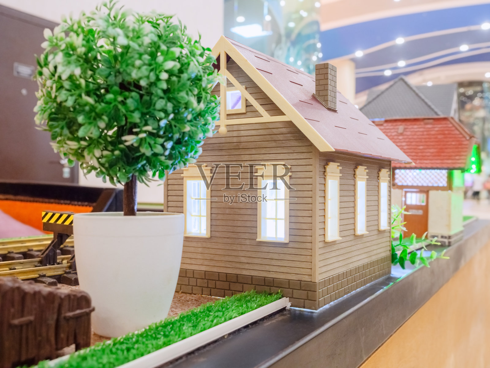 玩具米色的房子，装饰草坪和一棵树在一个白色的花盆照片摄影图片