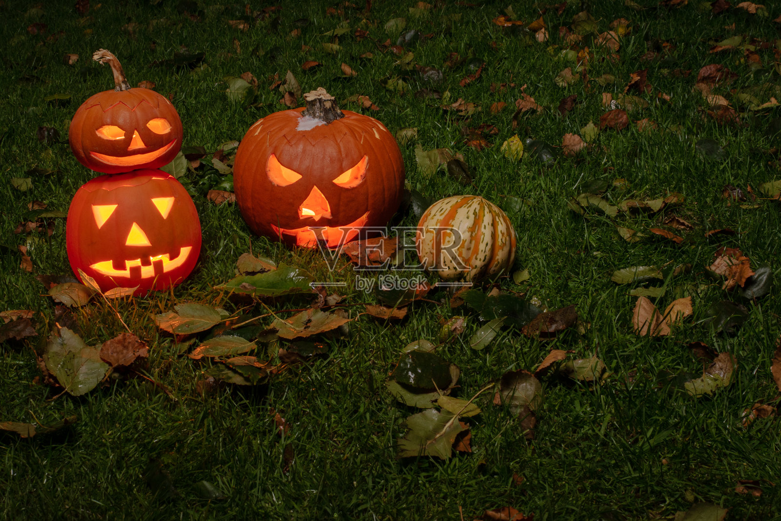 万圣节的南瓜头南瓜灯与可怕的邪恶的面孔和蜡烛。季节性照明装饰。照片摄影图片