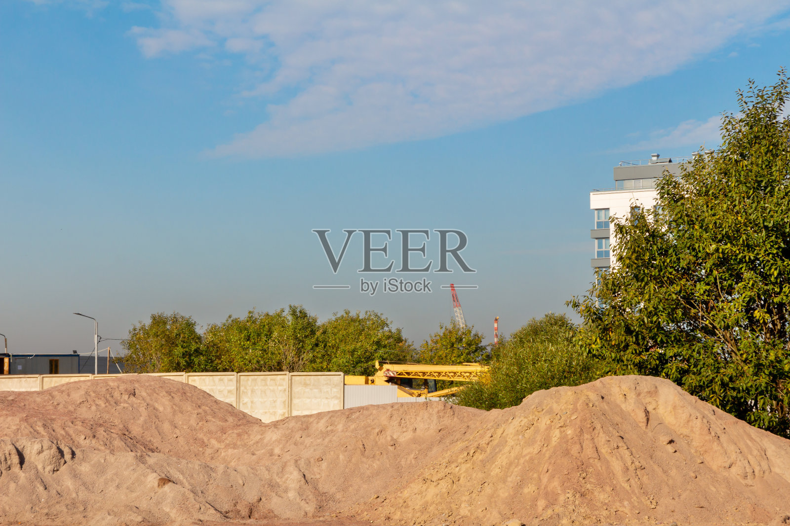 建筑工地的一堆沙子，映衬着天空和一栋公寓楼照片摄影图片