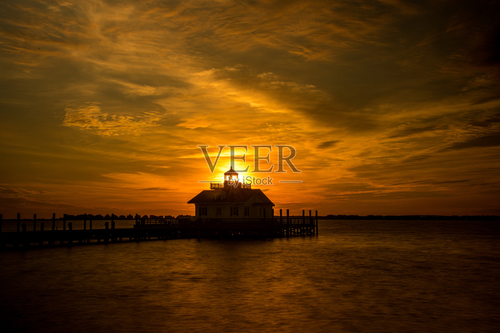 后面有太阳升起的灯塔照片摄影图片