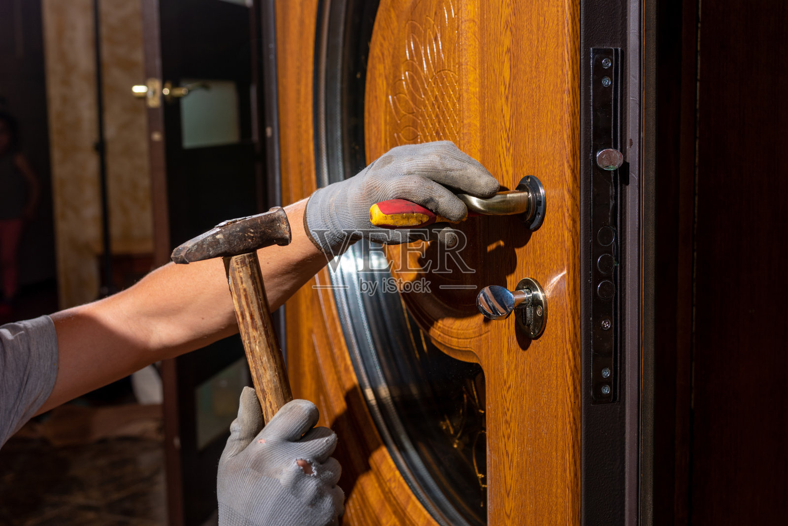 主工人在前门安装一个门锁，金属门上涂有聚合物涂层。照片摄影图片