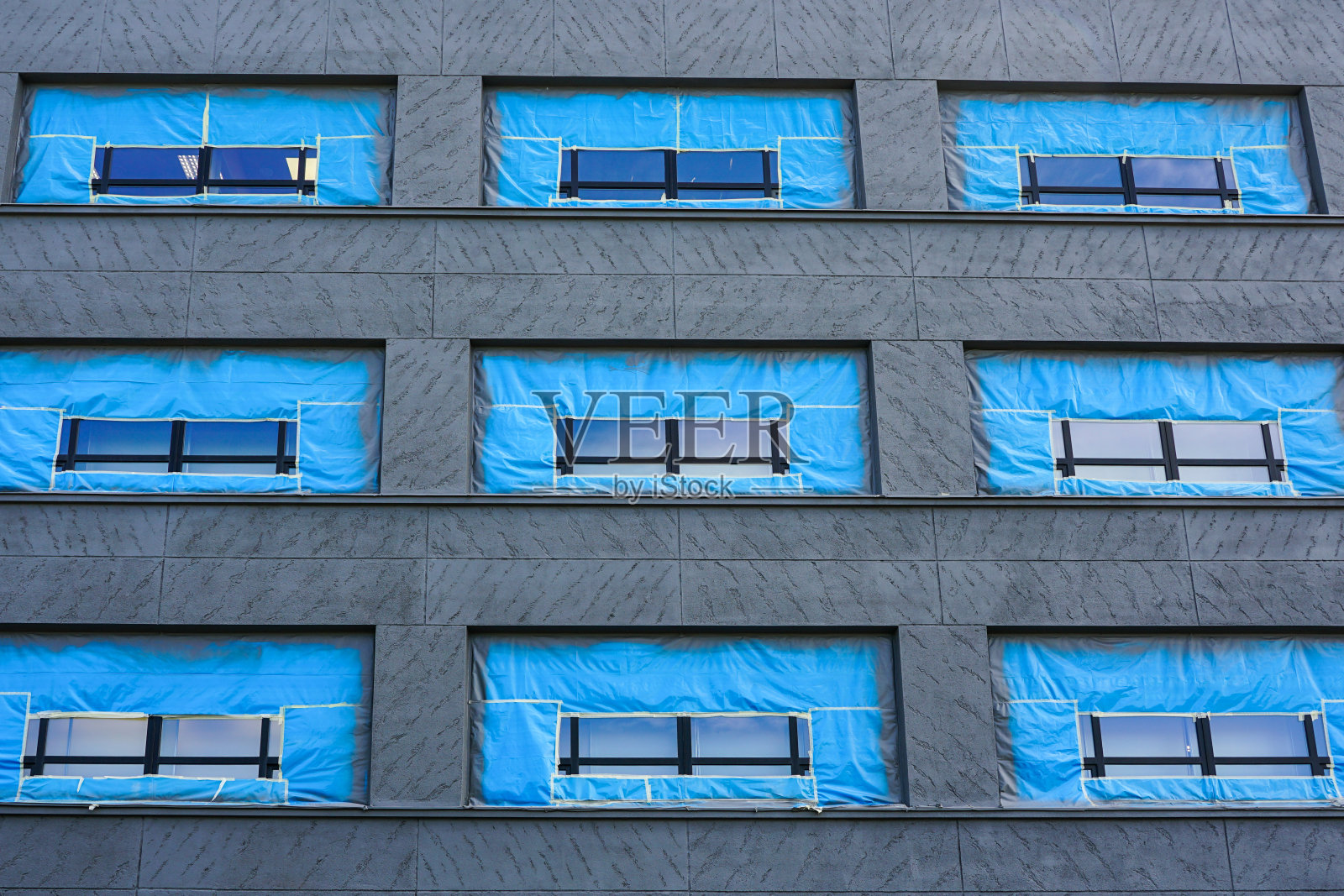 房屋正面油漆，窗户覆盖蓝色薄膜照片摄影图片