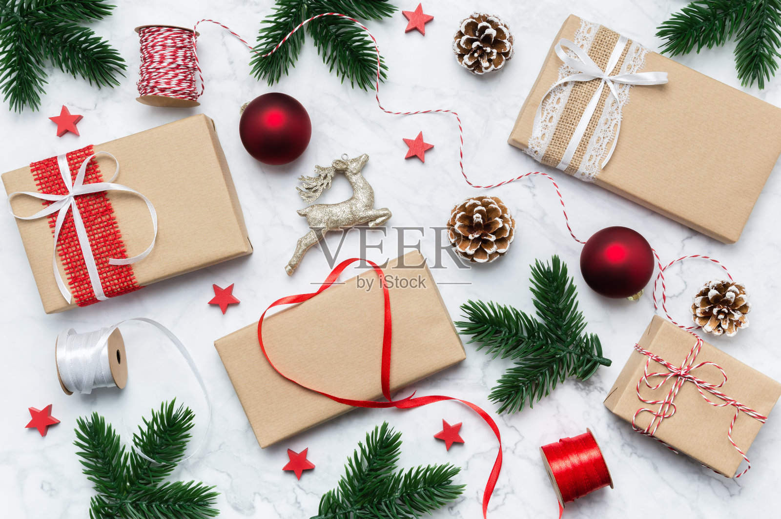 圣诞节手工礼品盒、树枝、松果、星星和驯鹿，大理石背景。圣诞礼物包装平面图。冬季节日主题。圣诞快乐，新年快乐照片摄影图片
