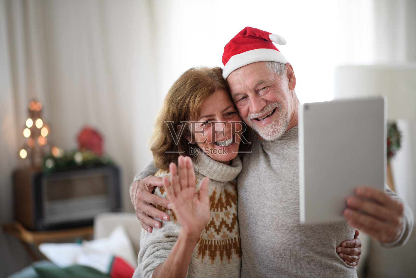 圣诞期间，戴着口罩的老夫妇在家里自拍。照片摄影图片