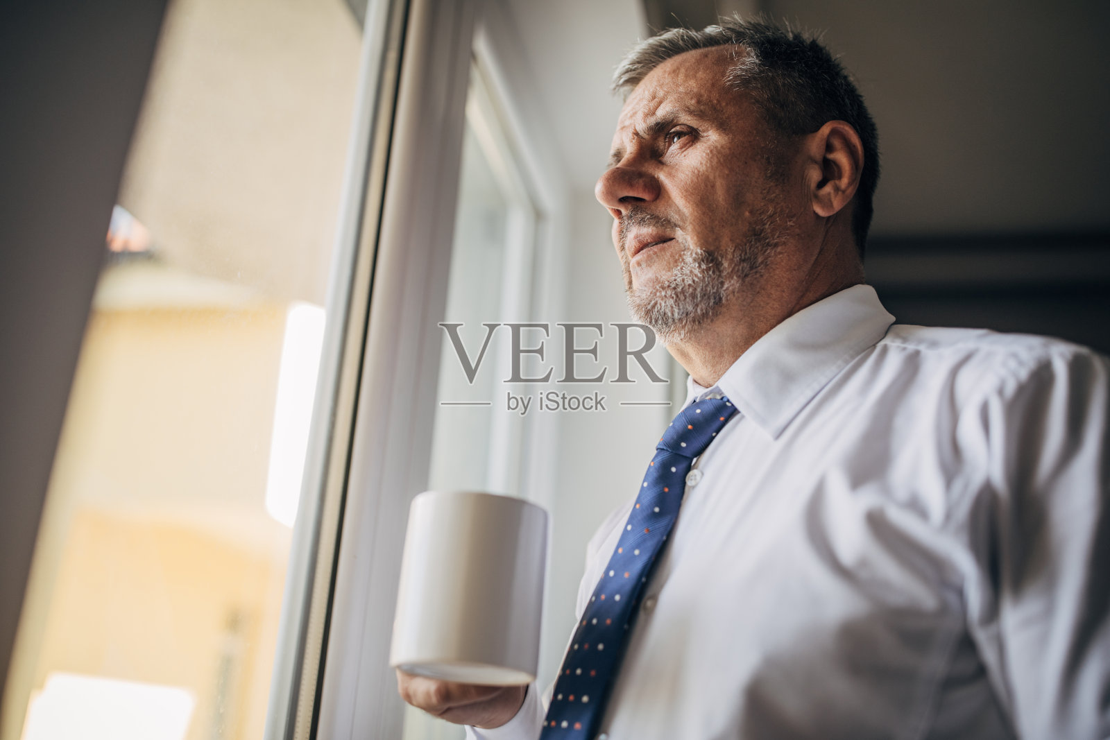 面对成熟的商人思考和看窗外照片摄影图片