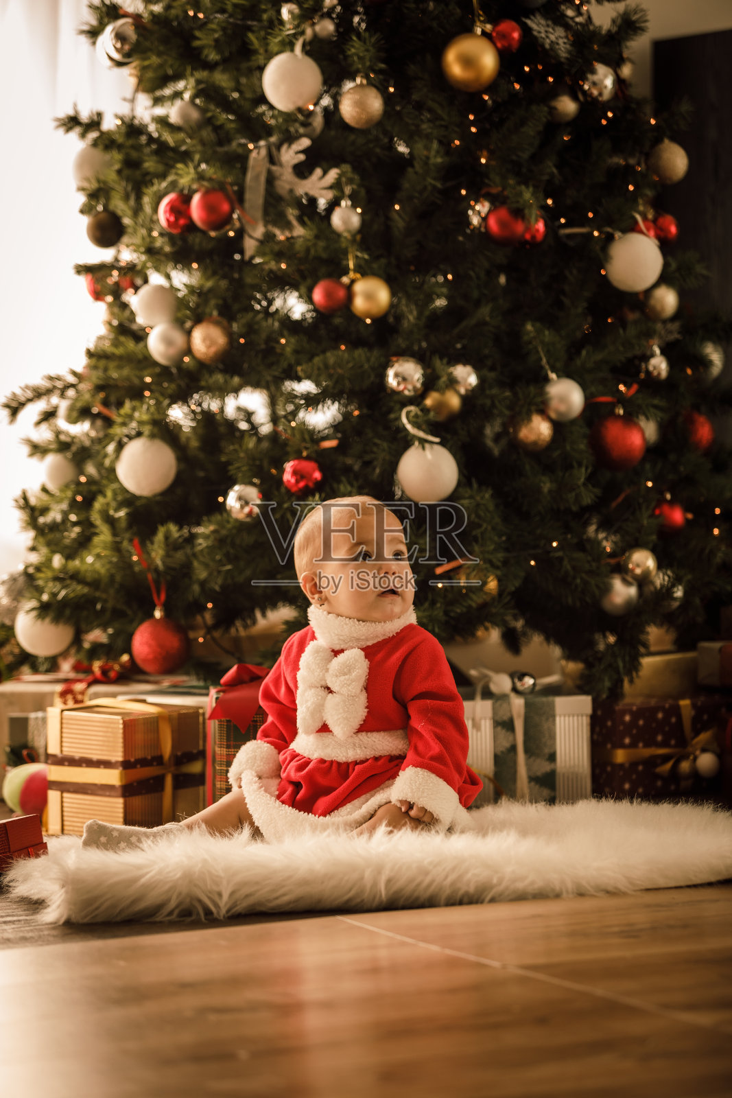 可爱的小女孩坐在圣诞树下照片摄影图片
