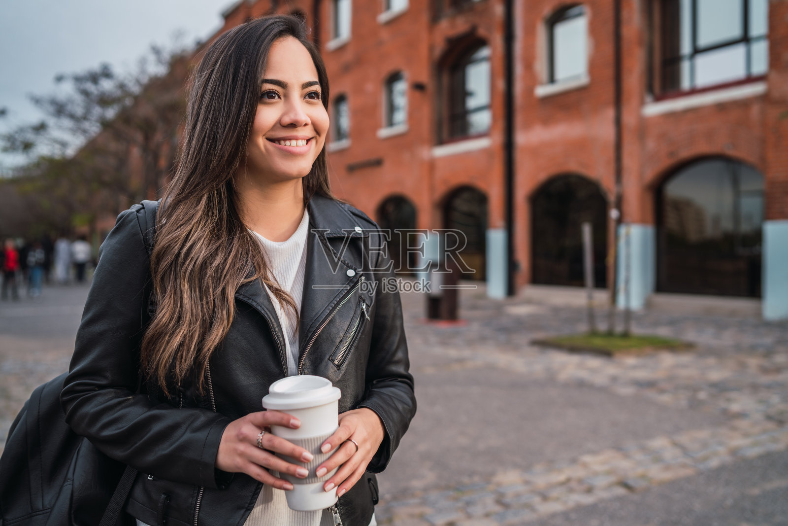 拿着一杯咖啡的年轻女子。照片摄影图片