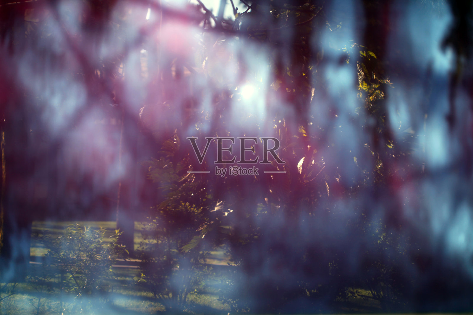 旧的、脏的、满是灰尘的窗户玻璃，反射着神秘的光。软的焦点。抽象背景与划痕。蓝色和洋红色。光的效果。照片摄影图片