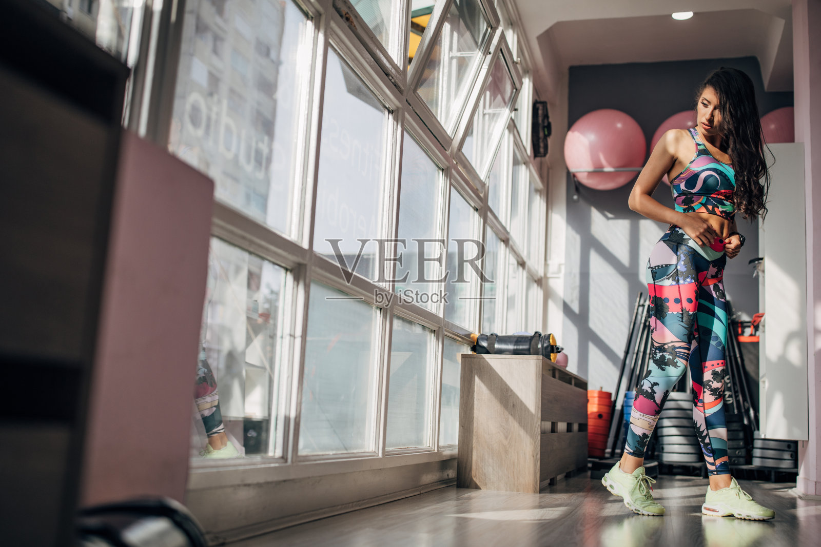 年轻的健身女士站在健身房里照片摄影图片