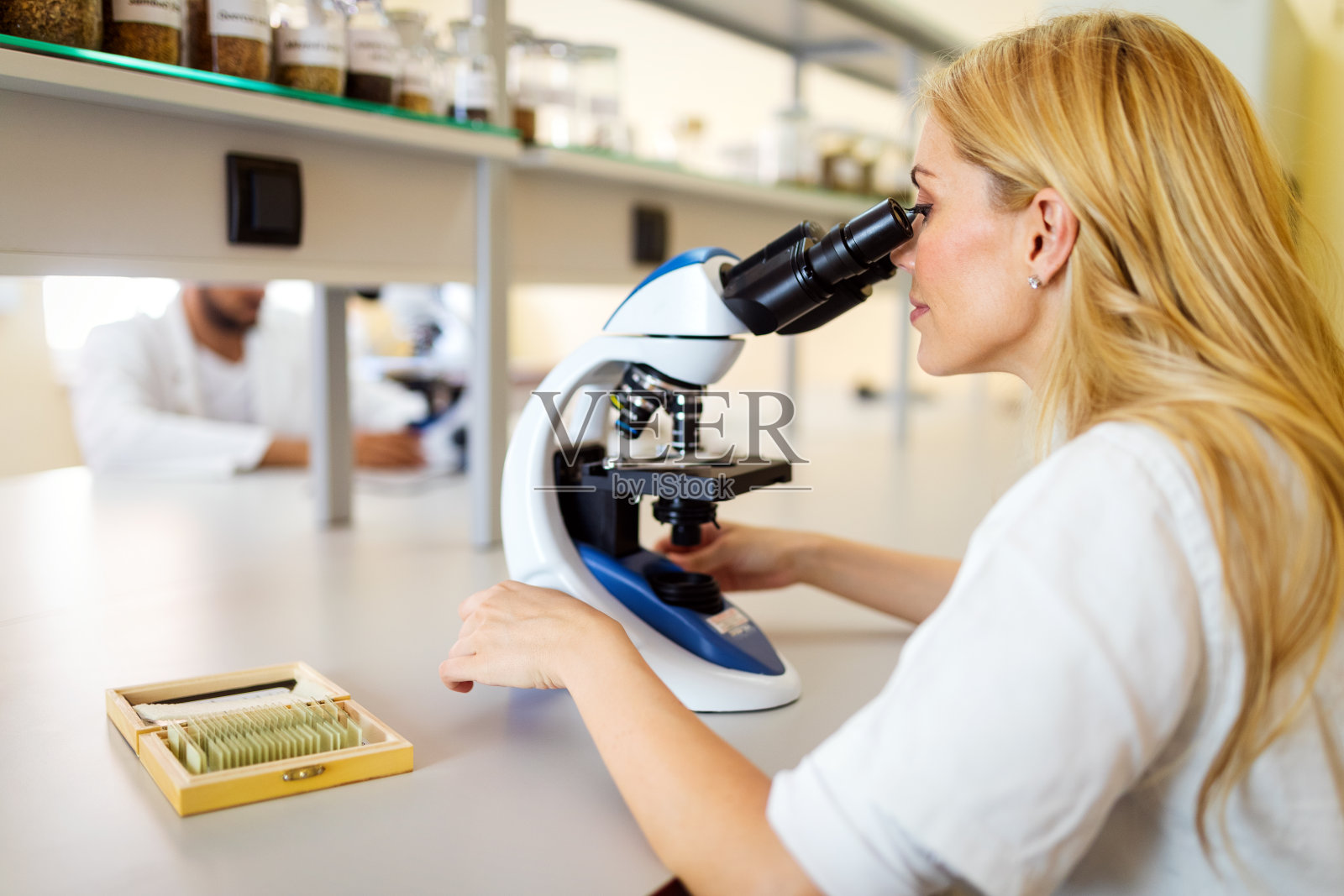 科学家在实验室使用显微镜，检测冠状病毒疫苗照片摄影图片